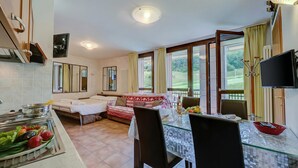 Uma cozinha moderna com área de refeições, um sofá-cama e uma televisão.