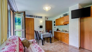 Espaço compacto com área de refeições, cozinha compacta e sofá com roupa de cama estampada.