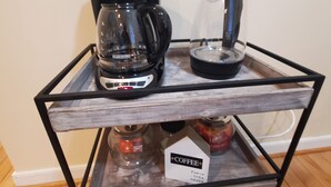 En kaffestation med en bryggkaffemaskin, en presskanna och en glaskanna, placerat på en metallvagn.