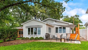 A single-story house with a covered patio, a grill, and a small deck.
