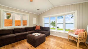 A living room with a sectional sofa, a rattan chair, and a wooden floor.