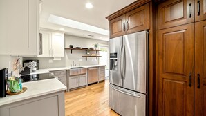 A modern kitchen with stainless steel appliances, wooden cabinets, and a white countertop.