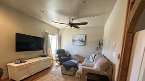 Un salon équipé d’un téléviseur à écran plat, d’un ventilateur de plafond, d’un canapé, d’une table basse et d’une petite table d’appoint.