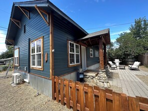 Una casa de dos pisos con fachada azul oscuro, detalles de madera y base de piedra.