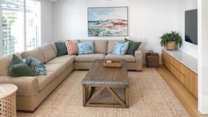Una sala de estar moderna con un sofá modular, una mesa de centro y un cuadro en la pared.