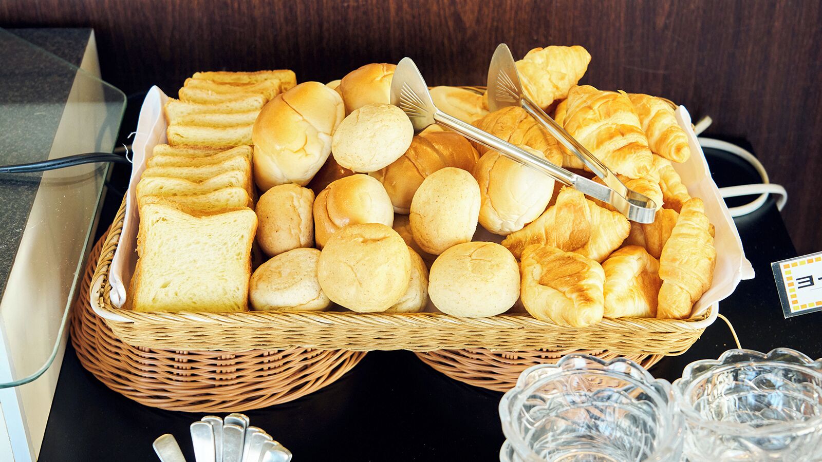 Ein Buffet mit verschiedenen Brötchen und Gebäck, darunter Croissants und Abendbrötchen, ansprechend in Weidenkorb-Körben angerichtet.