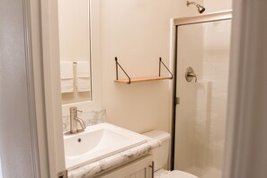 Ein Badezimmer mit Waschbecken, Spiegel, Dusche und Handtuchhalter.