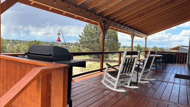 An outdoor deck with a grill, rocking chairs, and a view of a lighthouse. - NEW!  THE RETREAT Ranch House - Only 20 minutes from the Grand Canyon (Williams)