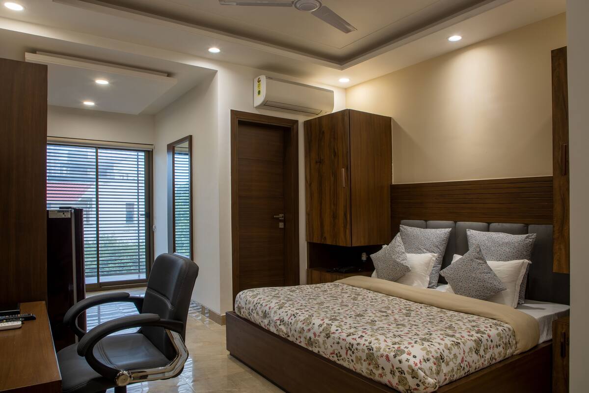 A bedroom with a bed, a desk, a chair, and a wardrobe.