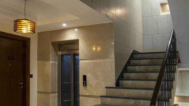 A modern interior with a marble staircase, a wooden door labeled '101', and an elevator. - Perch Service Apartments DLF Cyber City (Gurugram)