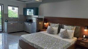 A modern bedroom with a large bed, a nightstand, and a built-in desk area. - Perch Service Apartments DLF Cyber City (Gurugram)