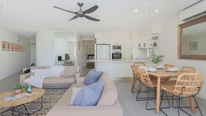 Ein modernes Wohnzimmer mit einer Couch, einem Couchtisch und einem Essbereich mit Korbstühlen.