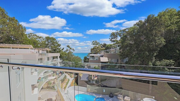 Ein moderner Poolbereich mit Glasgeländer, Liegestühlen und Blick auf das Meer.