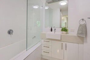 Enjoy a refreshing shower in this bathroom featuring a glass-enclosed shower area and a spacious vanity with ample storage.