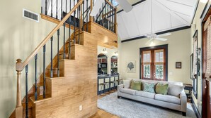 Ein geräumiger Wohnbereich mit einer Holztreppe, einer Couch und einer Essecke.