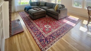 A spacious living room with a large sectional sofa, a patterned rug, and a fireplace.
