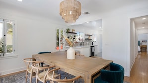 A dining area with a wooden table, woven chairs, and a chandelier.