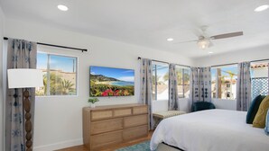 A bedroom with a bed, a wooden dresser, a floor lamp, and a ceiling fan.
