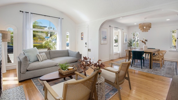 A spacious living room with a sofa, coffee table, and dining area with chairs and a table.