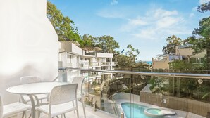 A balcony with a glass railing, a pool, and a table with chairs. - Penthouse 20 - The Cove (Noosa)