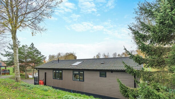 Un bâtiment moderne doté d’un toit plat, de grandes fenêtres et d’une petite structure adjacente.