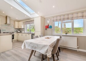 A modern kitchen with a dining area, skylight, and a view of greenery.
