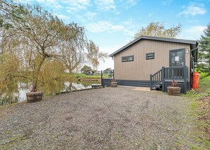 A building with a gravel driveway, a wooden dock, and a pond.