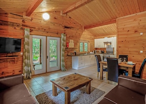 A wooden cabin interior with a living room, dining area, kitchen, and sliding glass doors leading to a deck. - 2 bedroom accommodation in Freehay, Cheadle (Freehay, Cheadle)