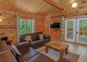 L'intérieur d'un chalet en bois, avec un canapé, un téléviseur et une table à manger.