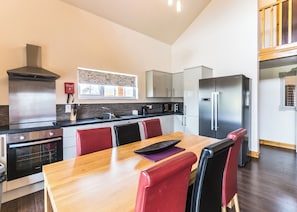A modern kitchen with a dining table, chairs, a stove, oven, microwave, and refrigerator. - Outstanding, spacious and contemporary two storey lodge. (Hornsea)