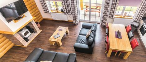 A modern living room with a sofa, a wooden table, a TV, and a view of the outdoors.