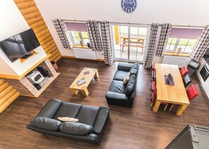 Ein modernes Wohnzimmer mit einer Couch, einem Holztisch, einem Fernseher und Blick ins Freie.