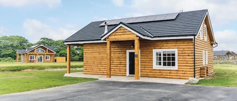 A log cabin with a pitched roof, a small porch, and a door with a number.