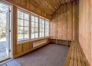 Une pièce aux murs en bois, avec une grande fenêtre, un banc et un radiateur.