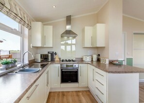A modern kitchen with white cabinets, a stainless steel range hood, a built-in oven, and a large window. - 2 bedroom accommodation in Swinethorpe, Nr Lincoln (Swinethorpe, Nr Lincoln)