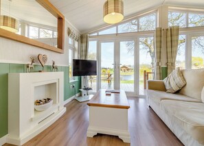 A living room with a fireplace, television, sofa, and large windows. - 2 bedroom accommodation in Swinethorpe, Nr Lincoln (Swinethorpe, Nr Lincoln)