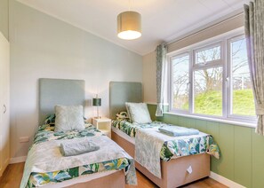 A bedroom with two beds, a window with curtains, a bedside lamp, and a hanging light fixture. - 2 bedroom accommodation in Swinethorpe, Nr Lincoln (Swinethorpe, Nr Lincoln)