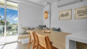 Ein moderner Essbereich mit einem Holztisch, Korbstühlen und einer Pendelleuchte.