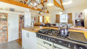 A kitchen with a stove, oven, and hanging pots. There is a dining area with a table and chairs.