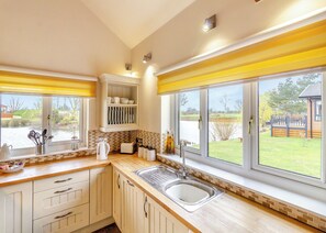 A kitchen with a sink, cabinets, and a window overlooking a garden. - Traditional two bedroomed lodge with two double rooms. (Swinethorpe, Nr Lincoln)