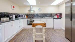 Una cucina moderna con mobili bianchi, un tavolo di legno, un frigorifero in acciaio inossidabile e un lucernario.