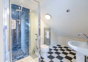Une salle de bain moderne avec une douche à parois de verre, des toilettes blanches, un carrelage noir et blanc à motifs et un lavabo blanc.