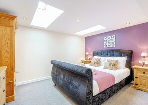A bedroom with a bed, nightstands, a wardrobe, and skylights. - Traditional and stylish converted two storey historic coach house. (Calthwaite, Nr Penrith)