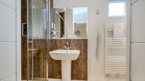 Un bagno moderno con cabina doccia in vetro, un lavandino bianco e un porta asciugamani.