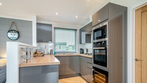 Una cucina moderna con isola centrale, forno integrato e finestra con persiane.