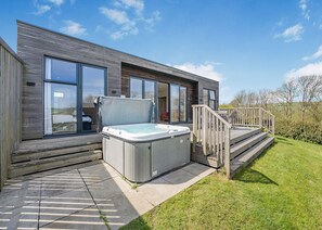 Uma casa moderna com banheira de hidromassagem, janelas amplas e um terraço.
