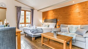 Une pièce confortable avec un lit, un canapé, une table basse en bois et une fenêtre avec des rideaux.