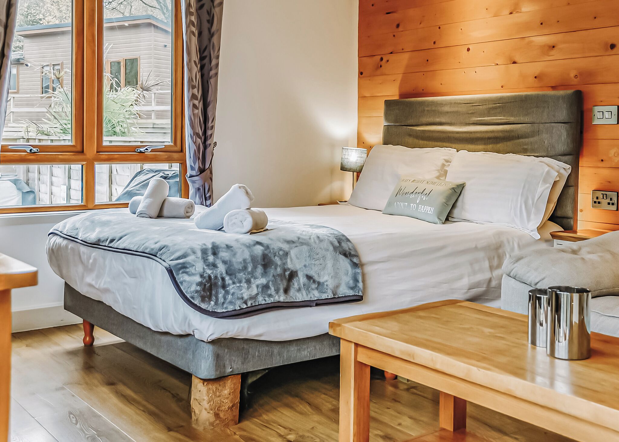 Une chambre à coucher avec un lit, une table de chevet, une lampe et une fenêtre avec des rideaux.
