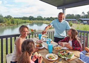 A dining area with a table set for four people, a lake view, and a covered deck.