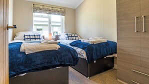 Une chambre avec deux lits, une fenêtre avec des stores, une armoire et une porte.